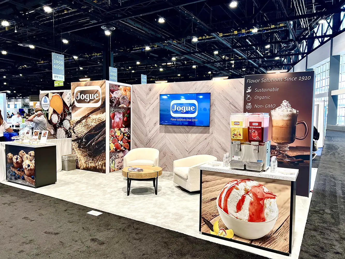 Jogue's trade show booth with signs, furniture and photos and a drink fountain.