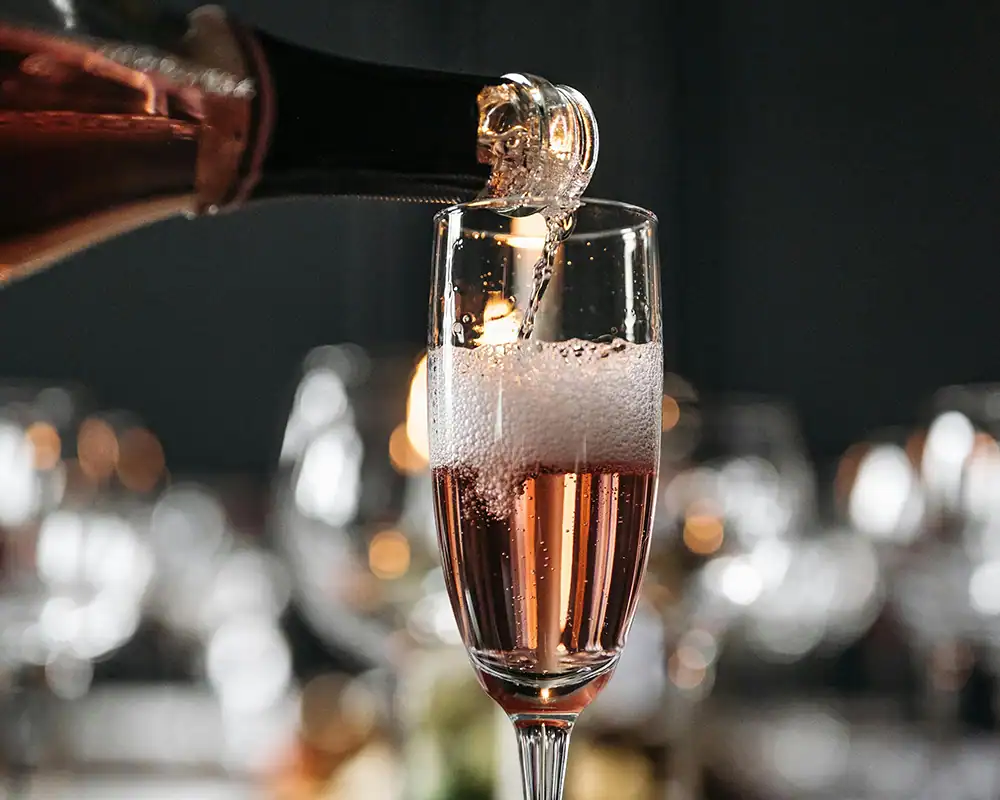 Close-up of champagne being poured out of a bottle neck into champagne glass.