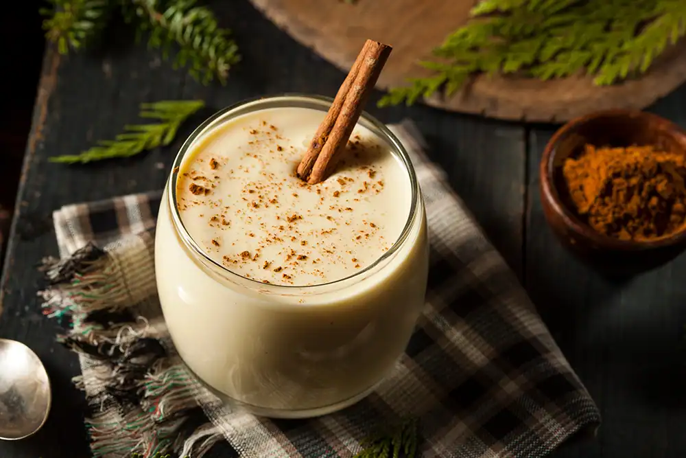 Glass of eggnog with cinnamon stick as a garnish.