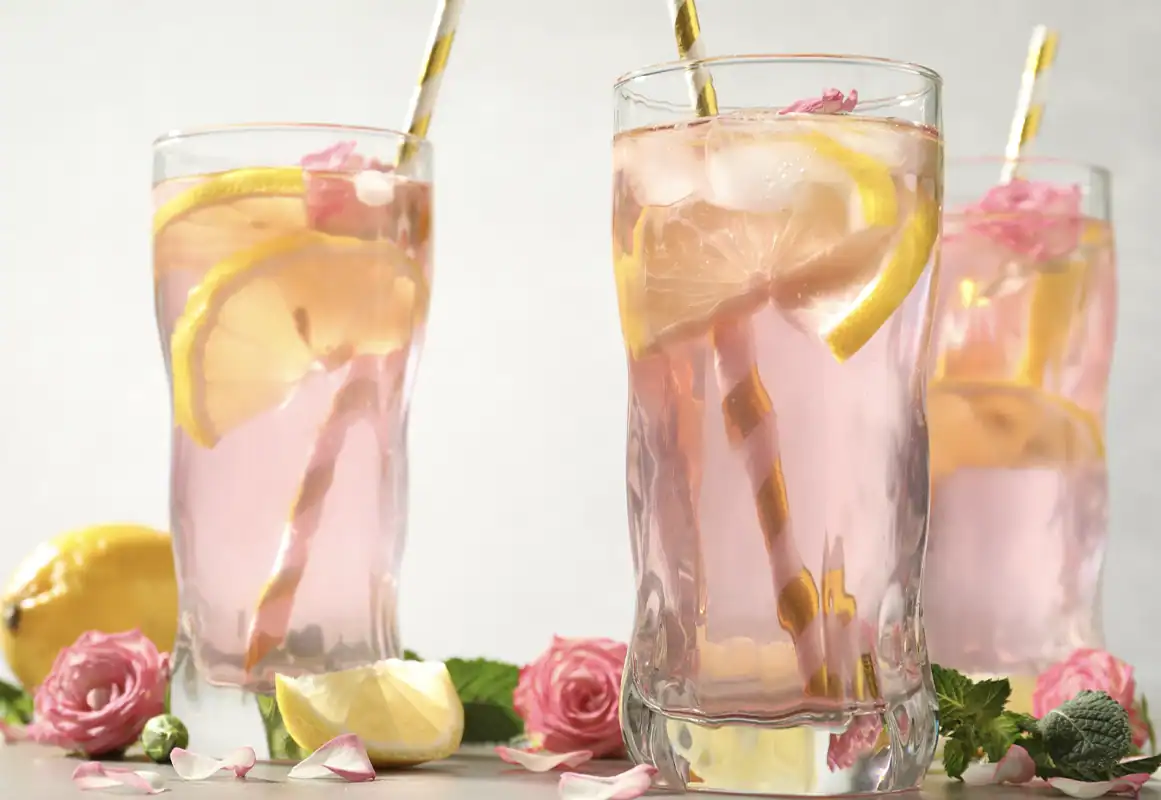 Glasses of a rose-flavored drink with lemon slice and ice.