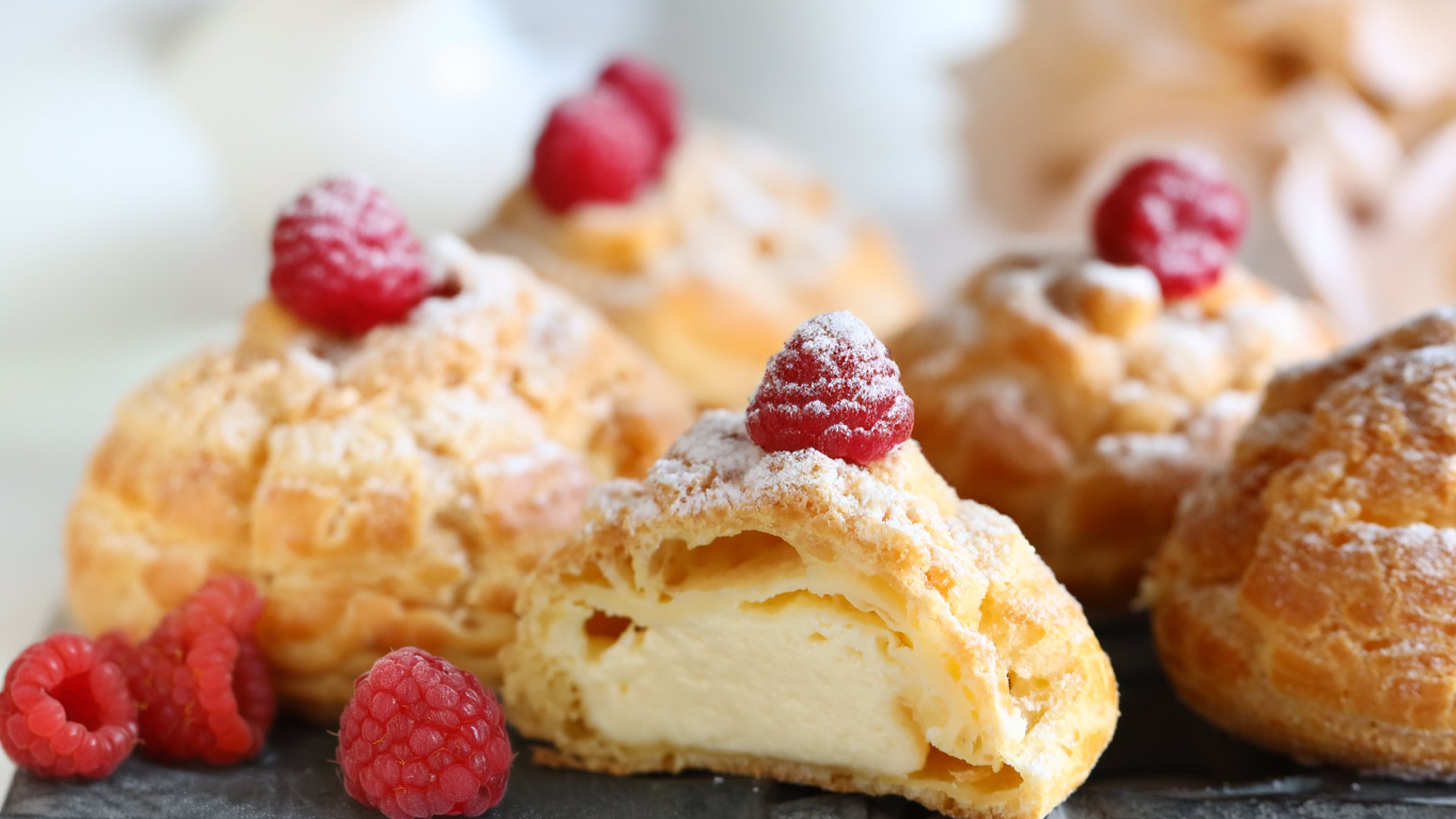 Cream puffs topped with raspberries and powdered sugar