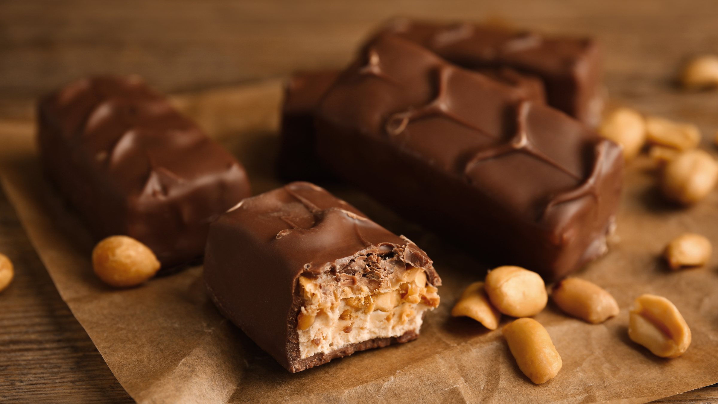Chocolate peanut bars on parchment with roasted peanuts