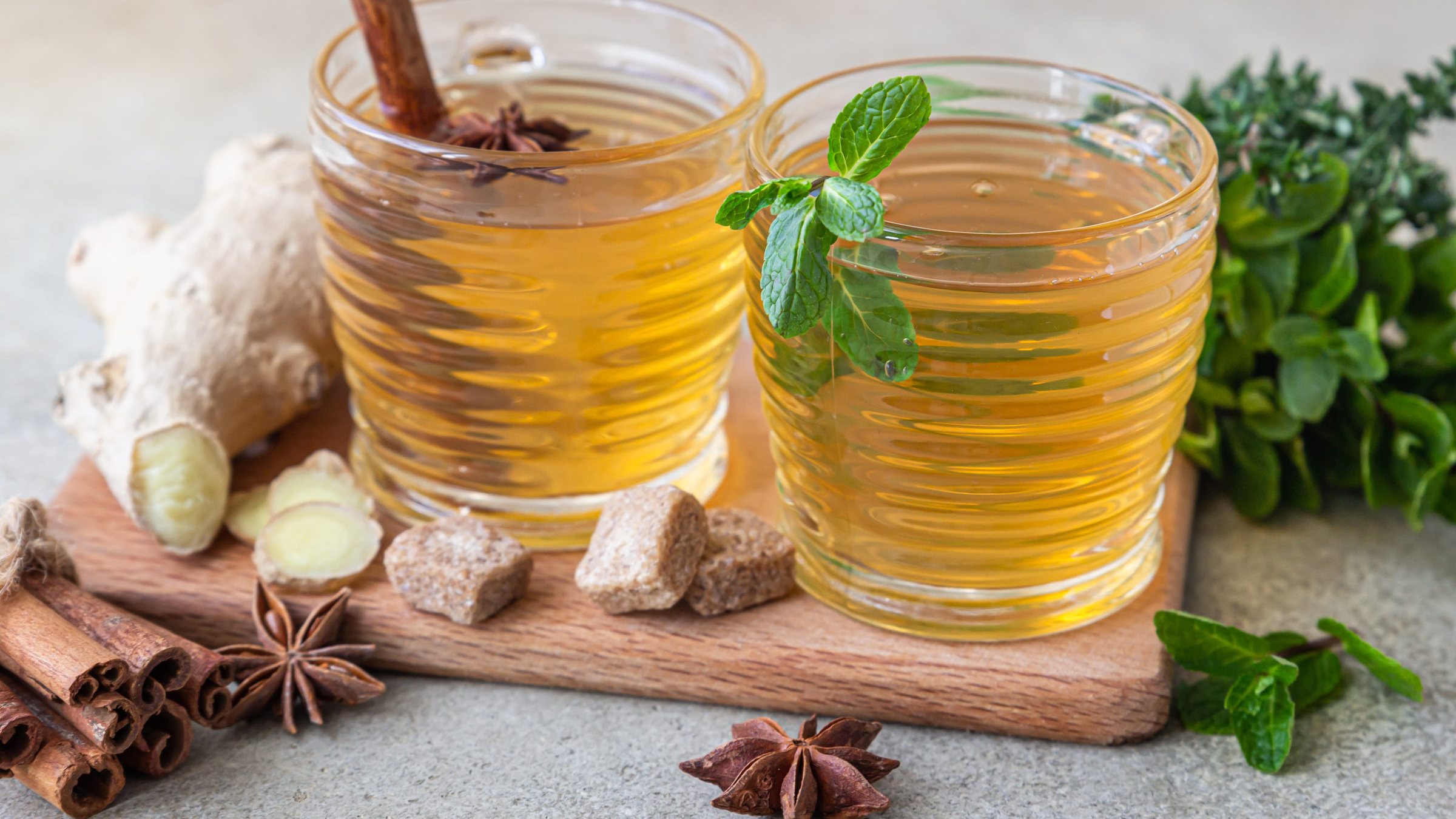 Two glasses of tea with ginger, cinnamon, star anise and mint